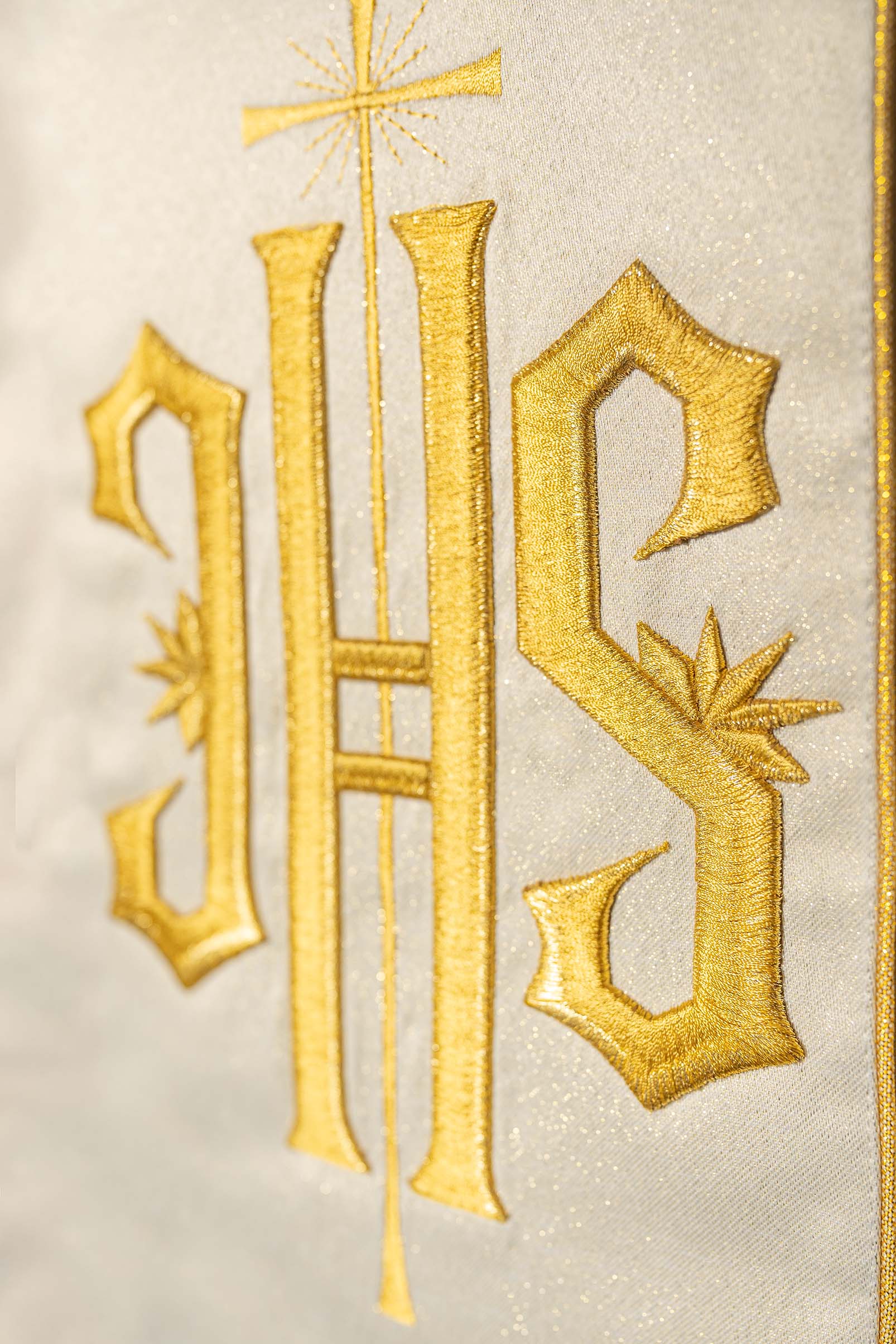 Casula dourada ricamente decorada com motivo dourado e faixa larga com símbolo IHS
