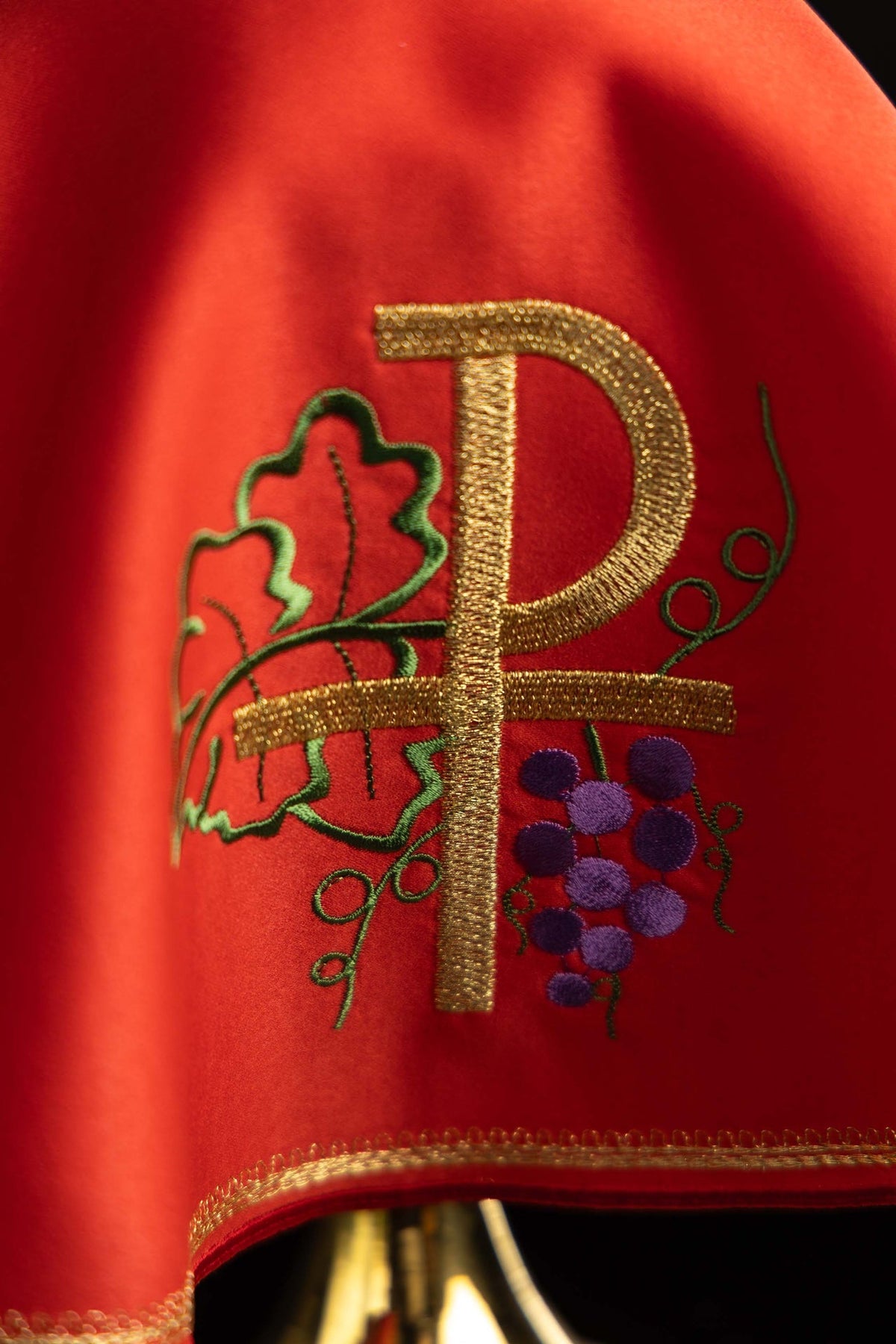 Cubrecopón rojo, detalle del bordado PAX dorado con uvas y hojas