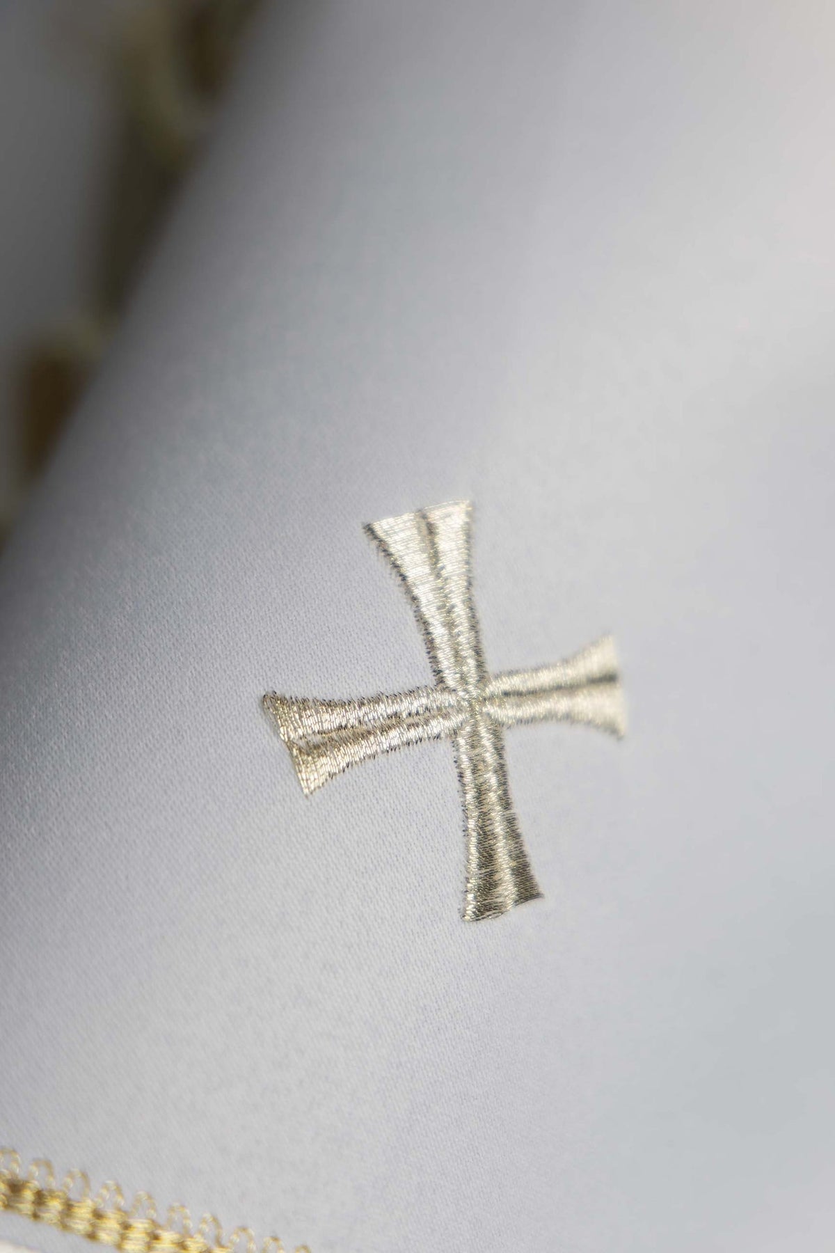 Cubrecopón blanco, primer plano de una cruz bordada
