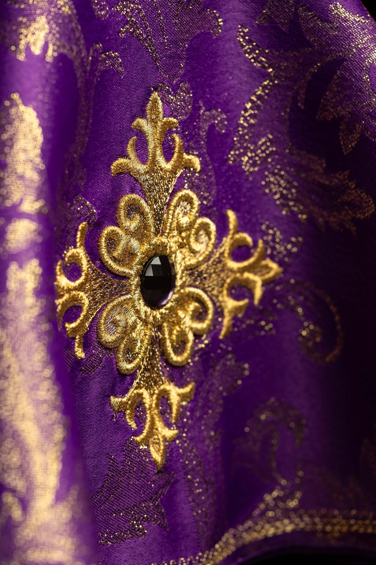 Cubrecopón morado con bordado dorado y piedra decorativa, detalle de cerca